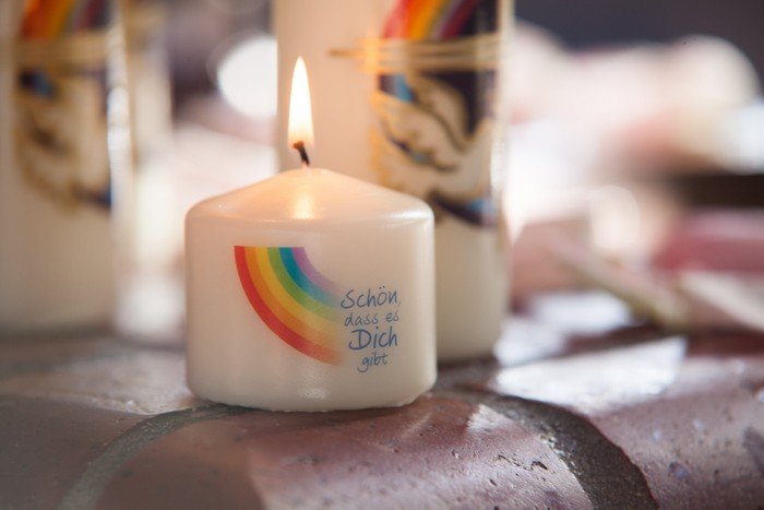 weiße Taufkerze mit Regenbogen und Spruch "Schön, dass es dich gibt".